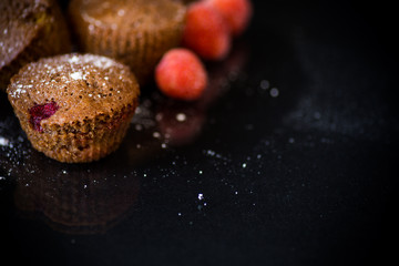fresh sweet muffins with berries inside on black