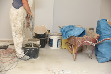 The construction worker mixes tile adhesive together with the water in the correct proportions.