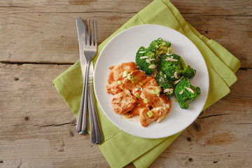 chicken breast fillet and broccoli with ginger on a green napkin and rustic wooden table, copy space, high angle view from above