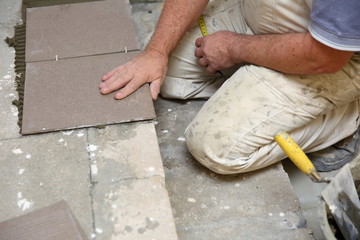  The builder arranges ceramic tiles on the stairs inside the building.