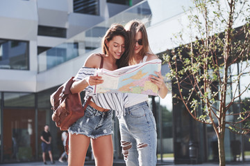 Two female tourist with map visiting a new city and is looking for a way to the hotel