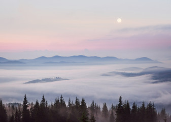 Beautiful sunset in the mountains. Landscape with sun light shining through orange clouds and fog