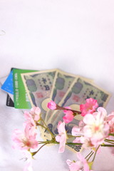日本のお金(お札)とクレジットカードと桜の花(白背景)