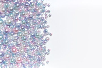 Horizontal texture of round pearl beads of different sizes and space for writing on a light background.