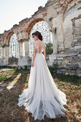 Fototapeta premium Beautiful bride in wedding dress, which is photographed on the wedding day near the old castle.