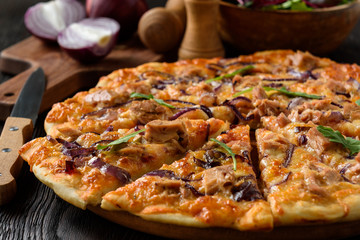 Homemade tuna and mozzarella pizza on wooden background.