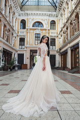 Obraz premium Beautiful, elegant bride with a perfect wedding dress, poses around beautiful architecture.