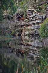 Fototapeta na wymiar Sandstone rock face and cliffs reflected in the still waters of the Port Hacking River, Audley, Royal National Park, NSW, Australia