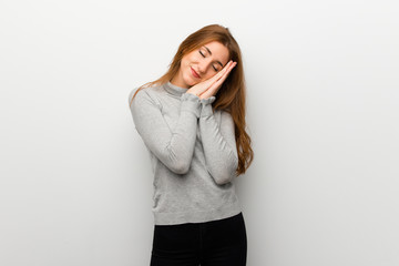 Redhead girl over white wall making sleep gesture in dorable expression