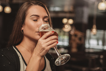 Close up of a gorgeous young woman enjoying drinking delicious beer at the restaurant. Beautiful...