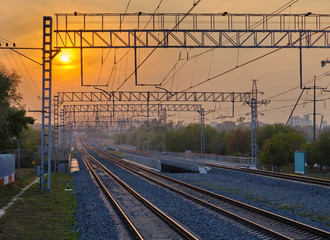 Railroad and communications against the setting sun and orange sky
