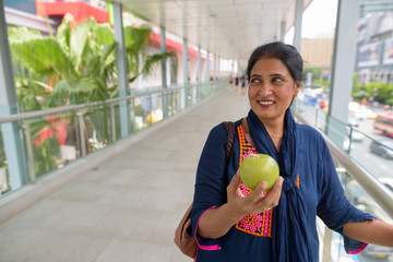 Mature beautiful Indian woman holding green apple fruit