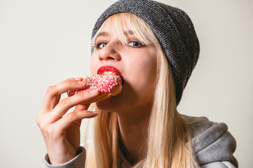 Beautiful girl eating a pink donut. Beauty, fashion, youth, enjoying the food, eat colorful donut....