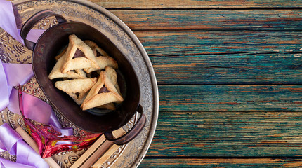 Jewish purim Hamantaschen homemade biscuits or cookies with purim mask and purim gragger. Top view or overhead composition with copy space