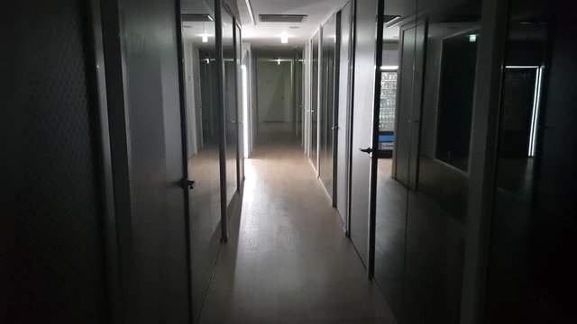Long corridor with glass wall and white door in the night