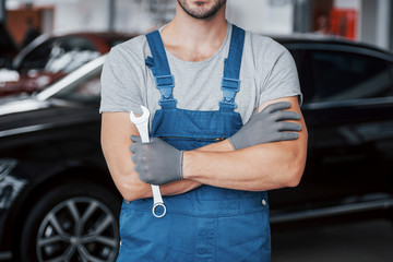 Hands of car mechanic with wrench in garage