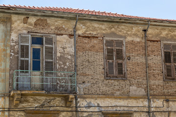 Destroyed wall of a residential stone house with windows .