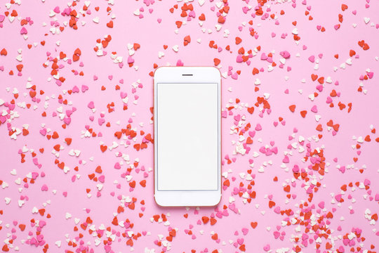 Mobile phone with pink and red hearts on pink background - Powered by Adobe