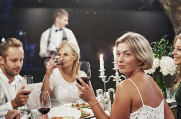 Elegant atmosphere. Group of adult friends have a rest and conversation in the backyard of...