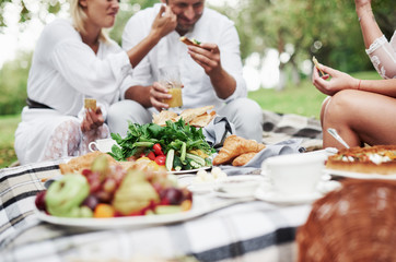 Vegetable food is on the table. Group of adult friends have a rest and conversation in the backyard of restaurant at dinner time