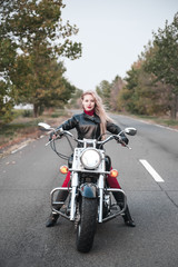Fototapeta na wymiar A stylish biker woman posing outdoor with motorcycle. 