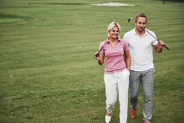 Sportive couple playing golf on a golf course, they stand to the next hole