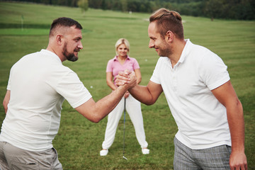 Fototapeta premium Three players play on the golf course. The team congratulates and shakes hands with each other