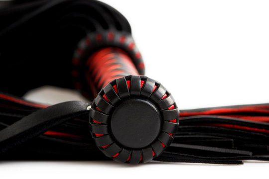 Red-black floger with a patterned handle and leather tails on white background.concept of pleasure from pain