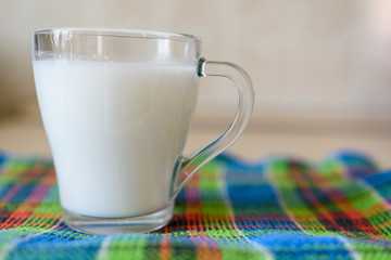 Morning glass of milk is on the kitchen table on a multi-colored towel.