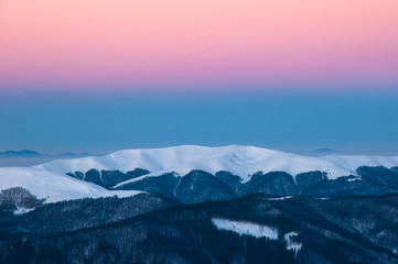 Fototapeta na wymiar Beautiful alpine panoramic views of the snow-capped mountains. Magic pink Sunrise in the mountains in a winter frosty day. Location Carpathian national park, Ukraine, Europe. Alpine ski resort.