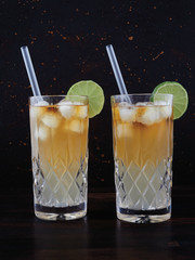 Dark 'n' stormy, a cocktail made using dark rum, ginger ale or beer, served in a highball glass filled with ice and garnished with a slice of lime