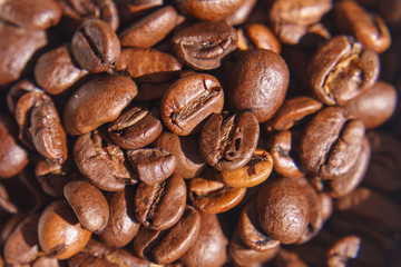 A pile of fresh brown coffee beans on a bright glass table on a sunny day with light available in a Close up