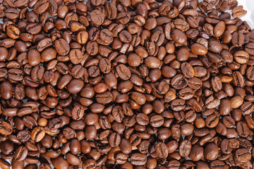 filled picture with a pile of fresh brown coffee beans on a bright glass table on a sunny day with light available