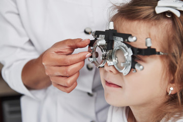 Focused photo of child in phoropter having testing his eyes in the doctor's office