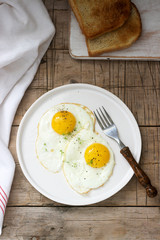 Breakfast of fried eggs, bread toasts and coffee on a wooden table. Rustic style.
