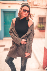 Stylish hipster young woman in a gray coat outside the home