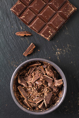Bakery preparation Flat lay chopped milk chocolate in the gray ceramic cup on black background with copy space