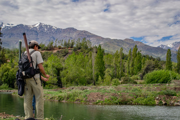 man catches a mountain view. on an artificial lake. sport fishing. man stands back. view of the mountains and the forest