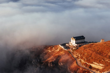 Fototapeta premium Lonely house. Hiking trail going near the hill with fog to the living building