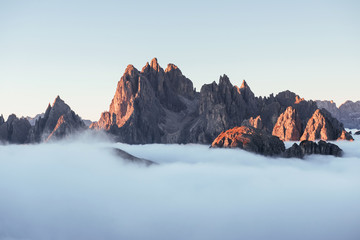 Rocks sleeping under all-encompassing mist. The peaks of the mountains stifle from a going thick...