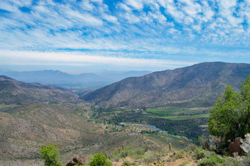 view of the valley between the mountains. view from above. to a residential valley. around the chilean mountains. below the village and ponds