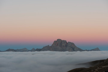 Variety of colors on the horizon. The peaks of the mountains stifle from a going thick fog. Unbelievable photo takes