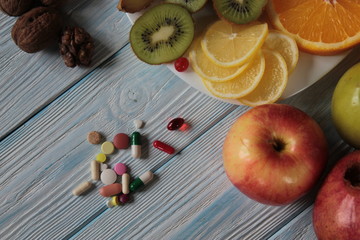 Fruit is on the plate -kiwi, oranges, lemon, pomegranate and tablets