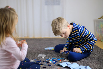 Two children playing with lots of colorful plastic blocks constructor.