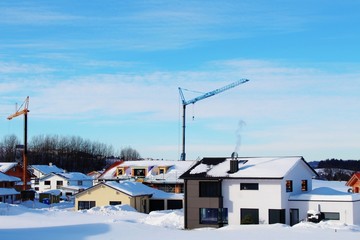 Neubausiedlung mit Baukränen in winterlicher Landschaft