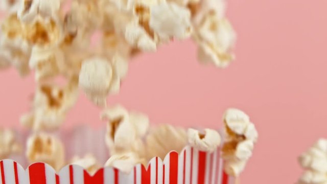 Falling popcorn in super slow motion on pink background.