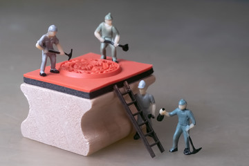 Miniature workers create rubber stamp, manufacturing concept