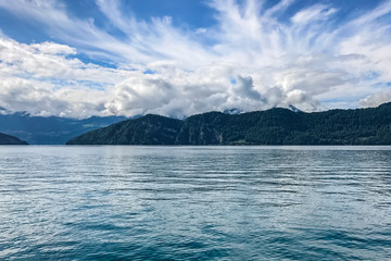 clear blue lake on a background of mountains, thick curly clouds over the lake