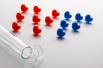 The broken test tube in the foreground and the letters of IVF from red and blue hearts. Concept of unsuccessful in vitro fertilization. The theme of shattered dreams and life. White background.