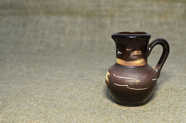 vintage small brown jug on grey textile background